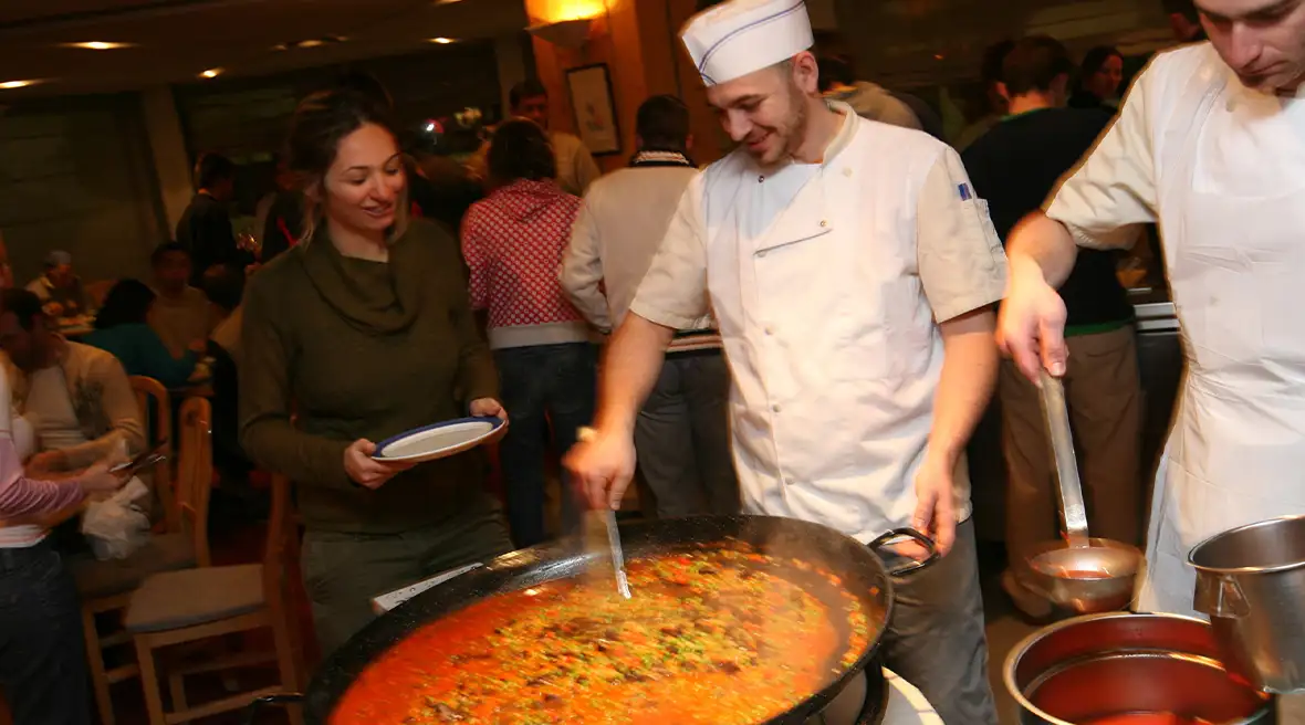 A chef serves from a huge paella dish