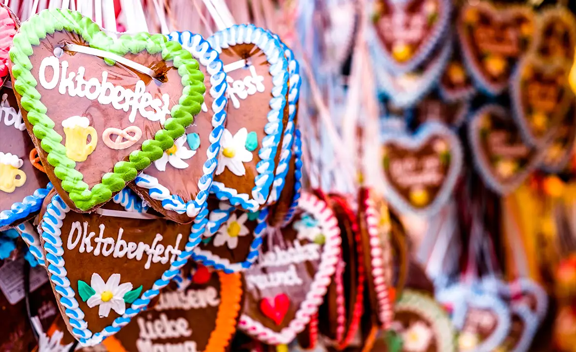 Heart shaped gingerbread hanging from ribbons with Oktoberfest written in colourful icing