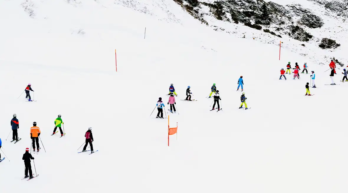 Skiers in different colored jackets skiing down a snow-covered mountain.