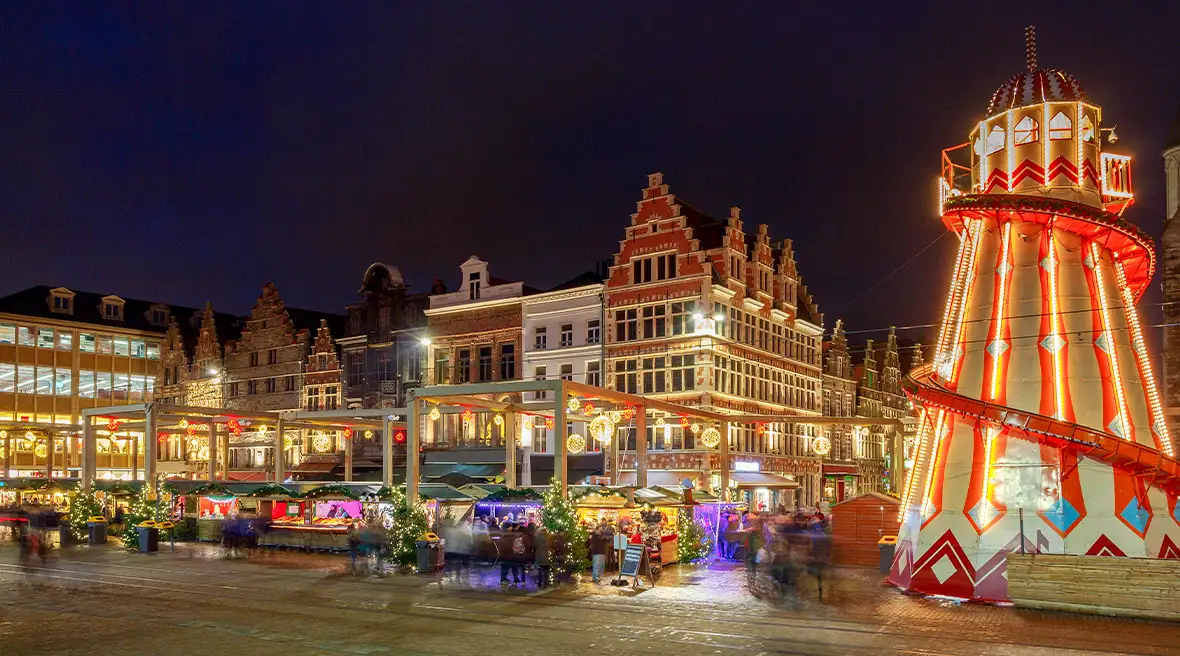 Buildings at night with Christmas market stalls and an amusement ride