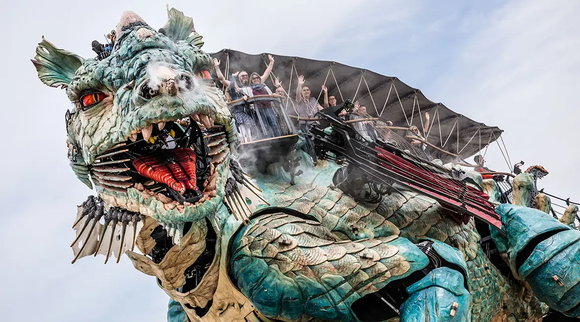 The face of the huge mechanical dragon looks down at the camera, its mouth open and teeth bared
