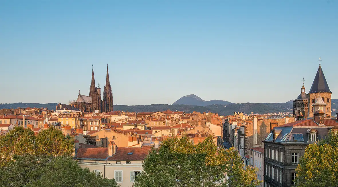 sunset looking over the rooftops of Clermont-Ferrand, the grey cathedral towers above the rest and in the distance sits Puy de Dome cathedral