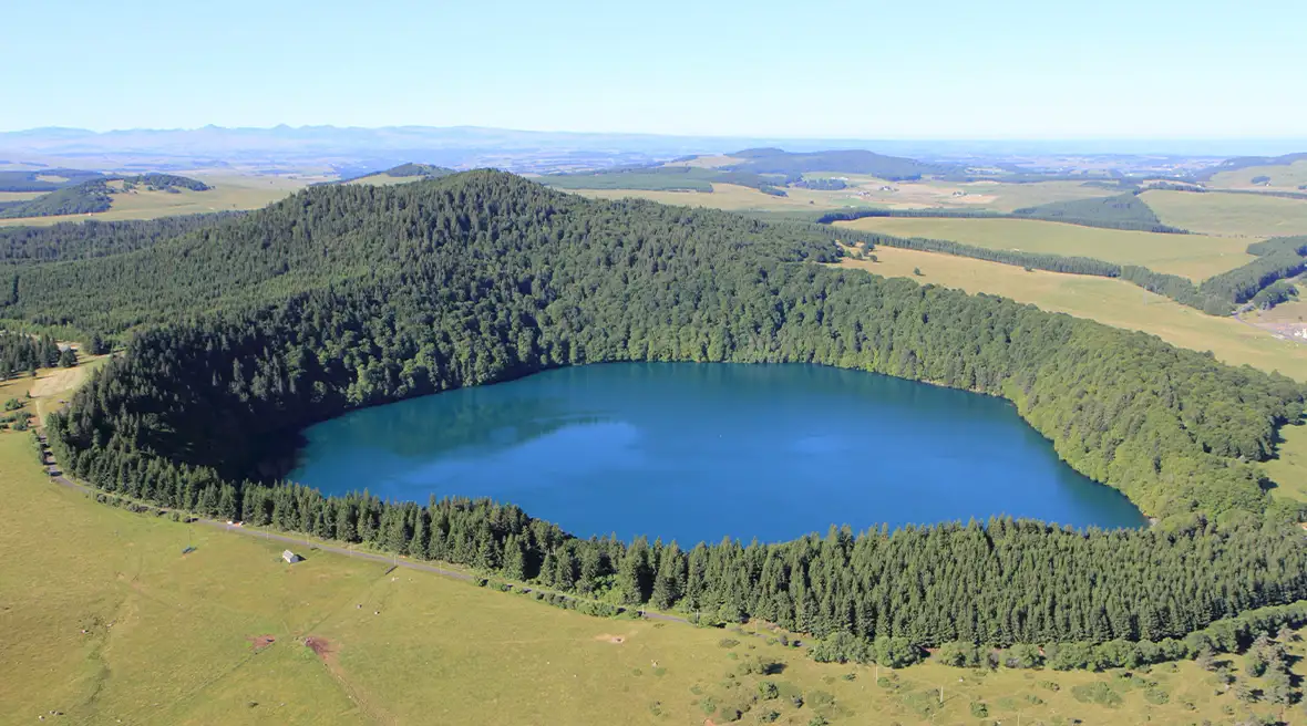 An aerial of a circular lake crater surrounded by thick woods
