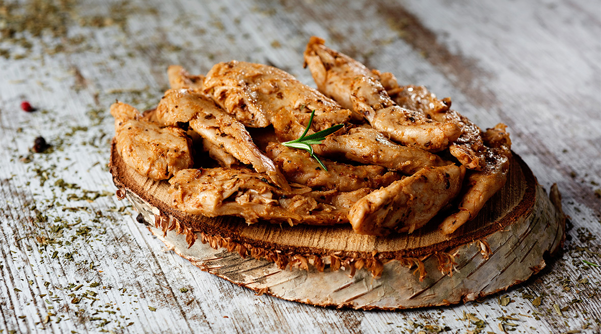 Strips of glazed chicken like meat served on a tree stump platter