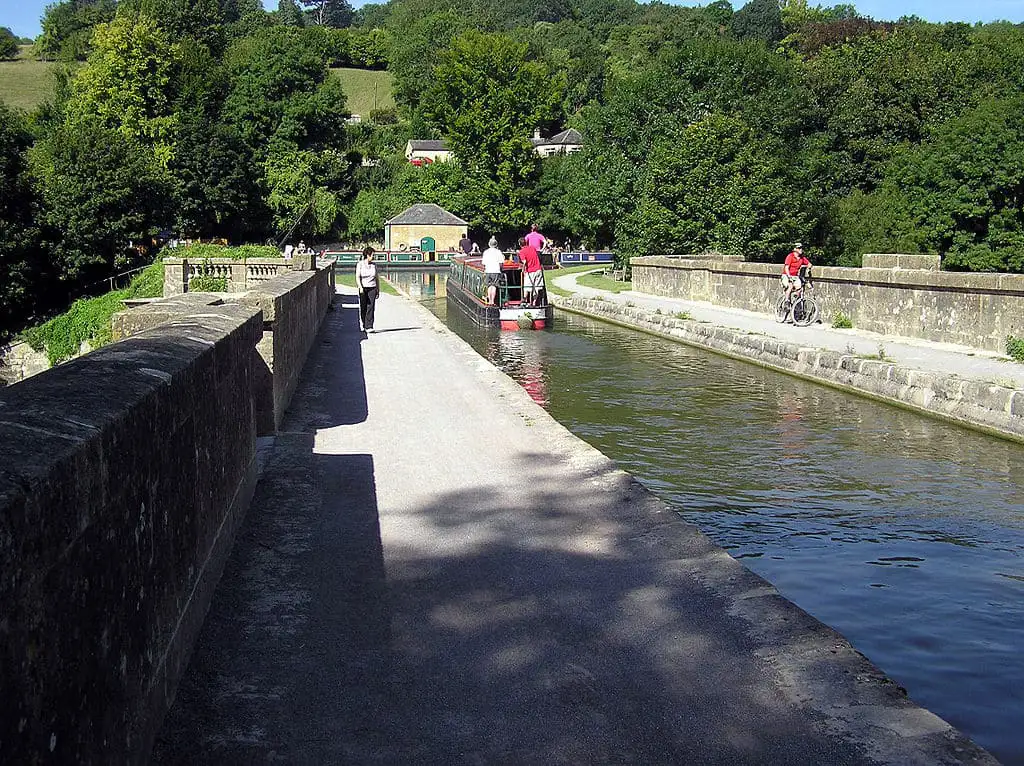 Mensen wandelen en fietsen over het historische Dundas-aquaduct terwijl een narrowboat passeert.