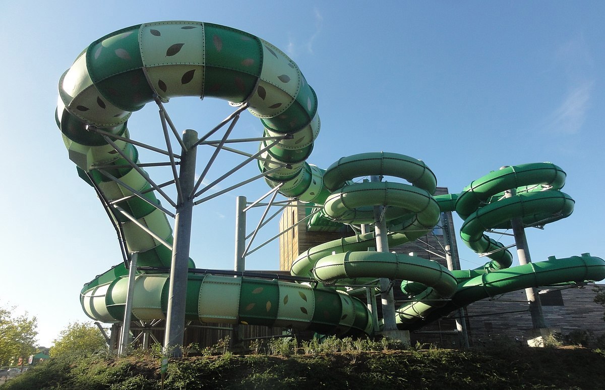 Green tube slide at Bellewaerde Aquapark, extending out of a building with several twists and turns.
