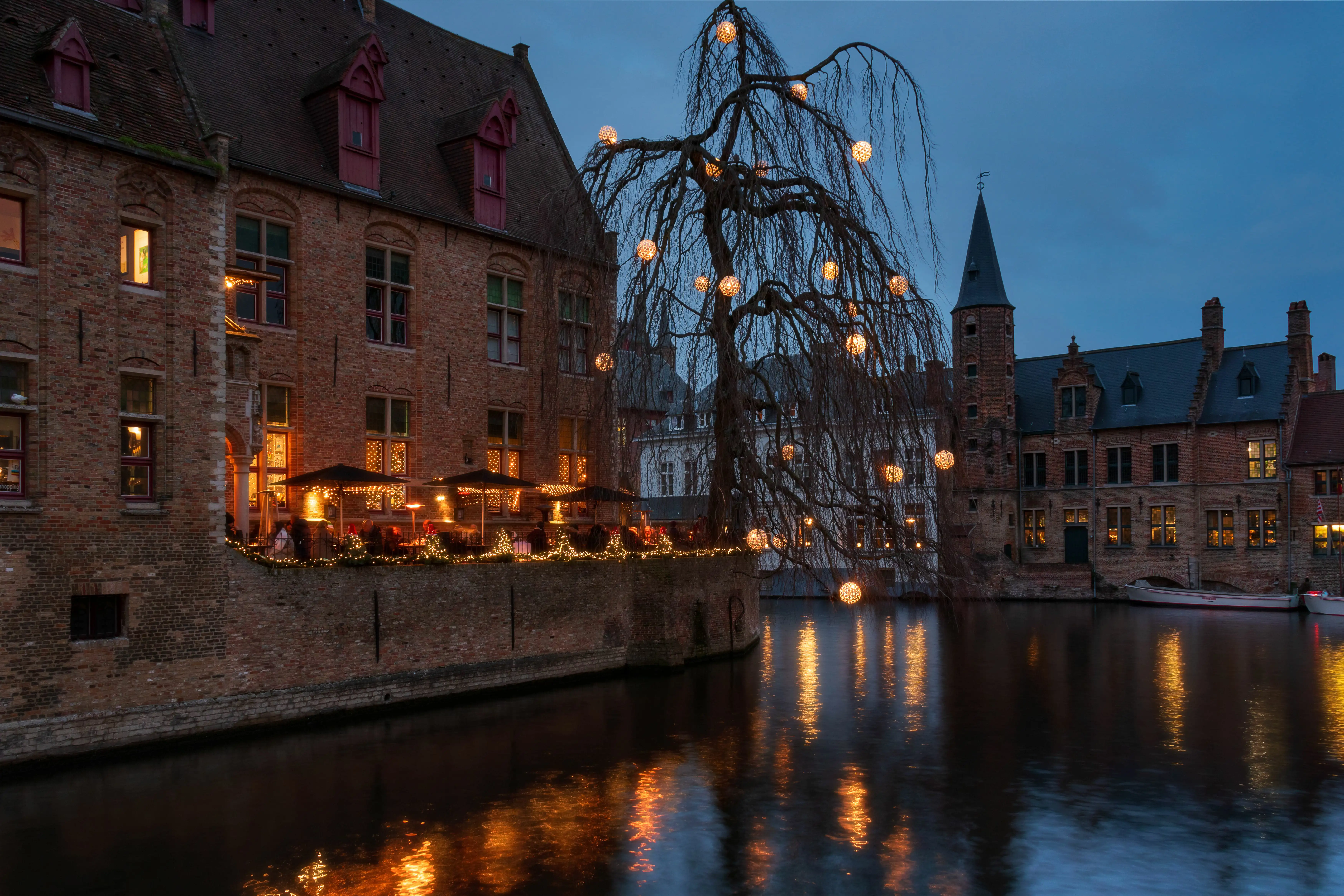 A canal-side bar sits in the background with it’s warm evening lights reflecting in the dark waters.
