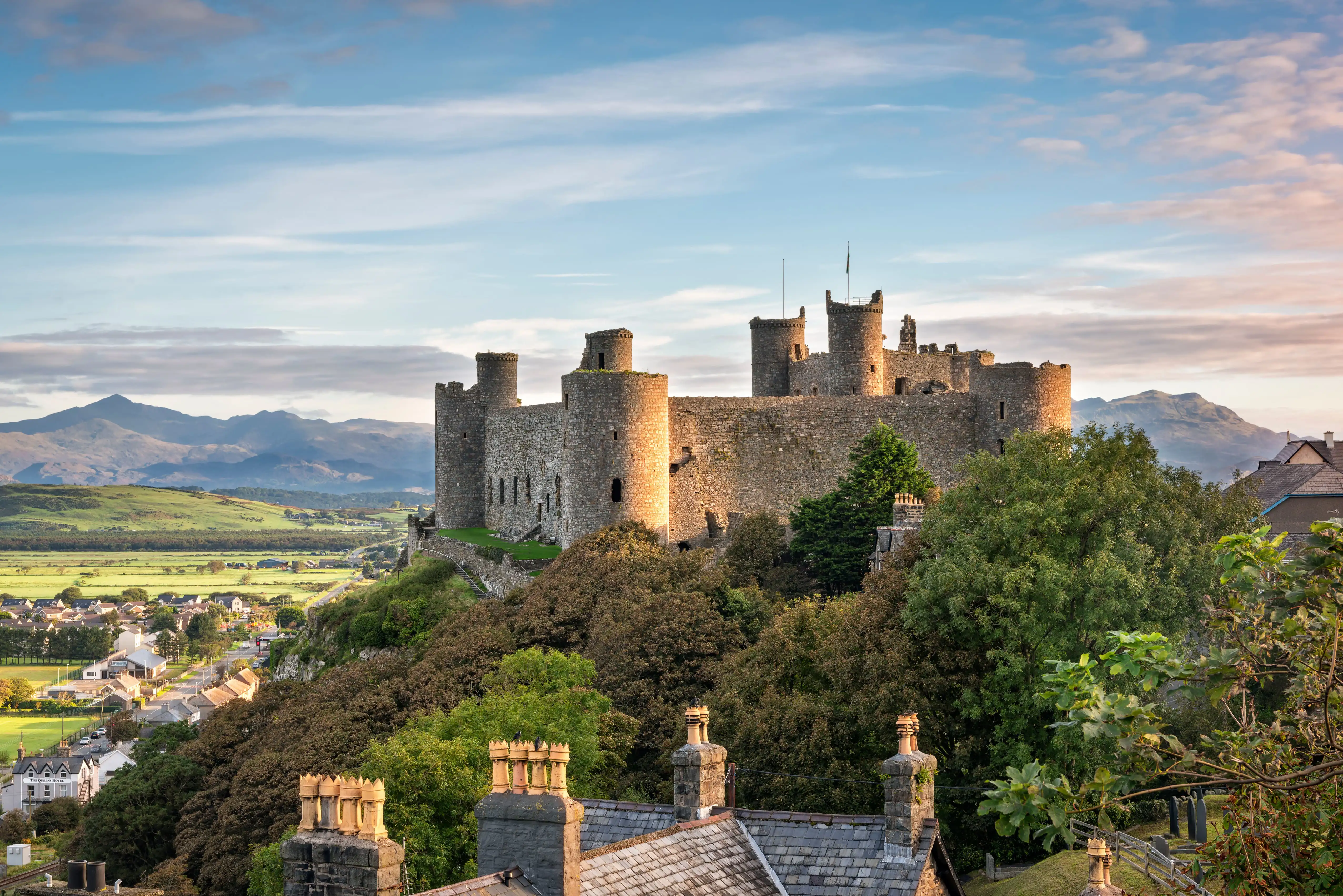 Kasteel Harlech gelegen bovenop een rotsachtige heuvel in Wales, met uitzicht op het omringende landschap en middeleeuwse stenen muren en torens