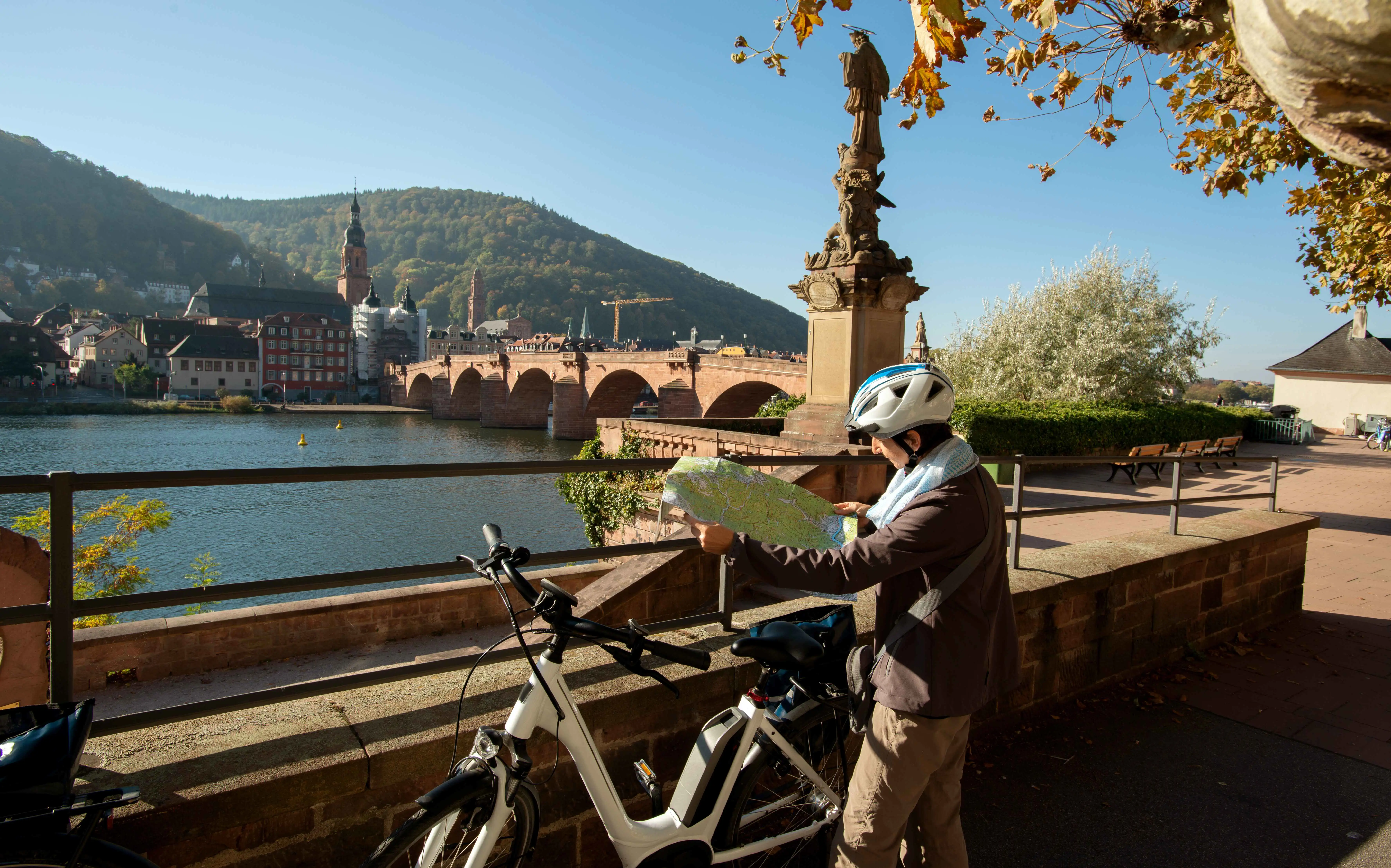 A person reads a map by a bike in front of the Old Bridge, Heidelberg, Germany