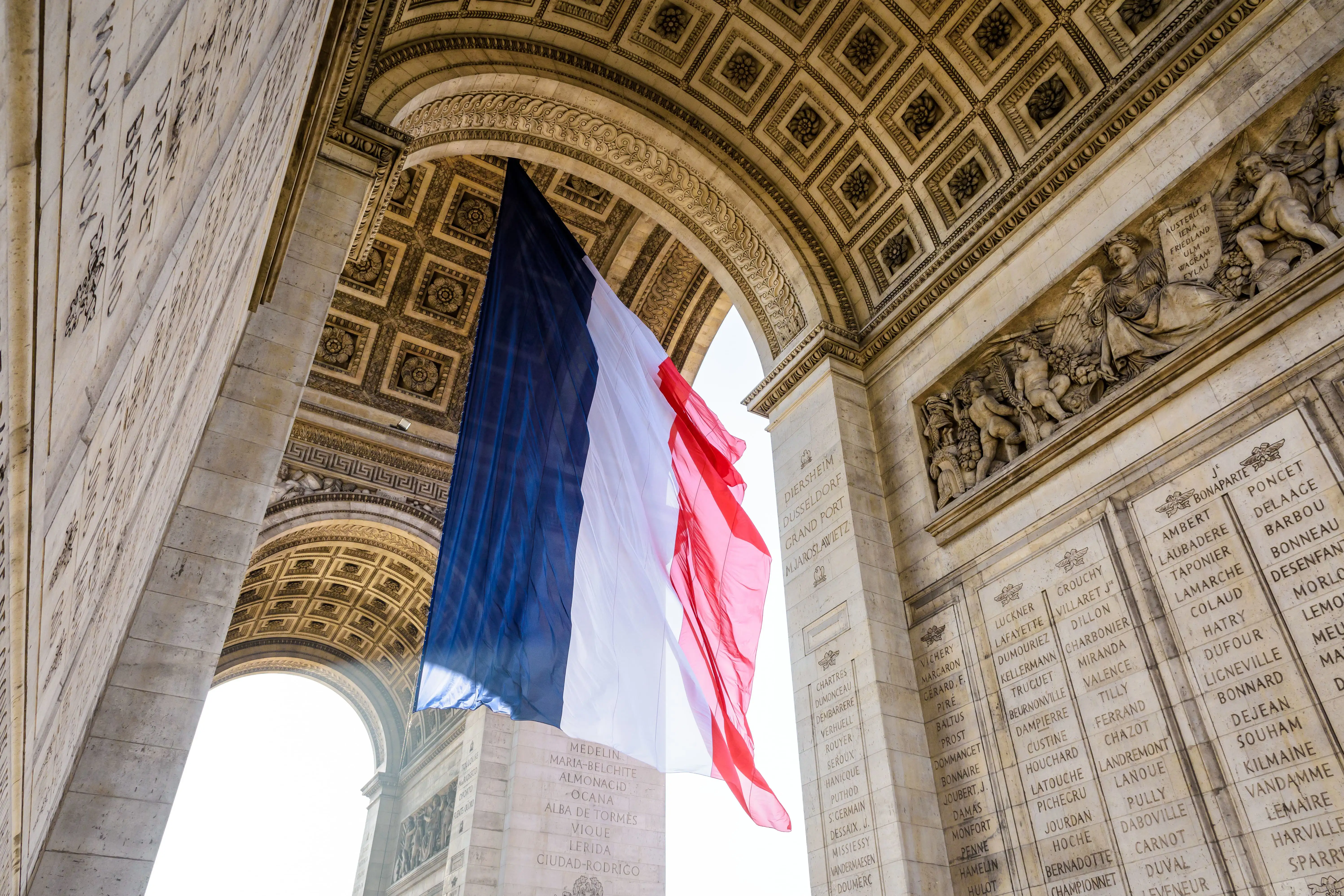 A French flag fluttering under the Arc de Triomphe in Paris, France