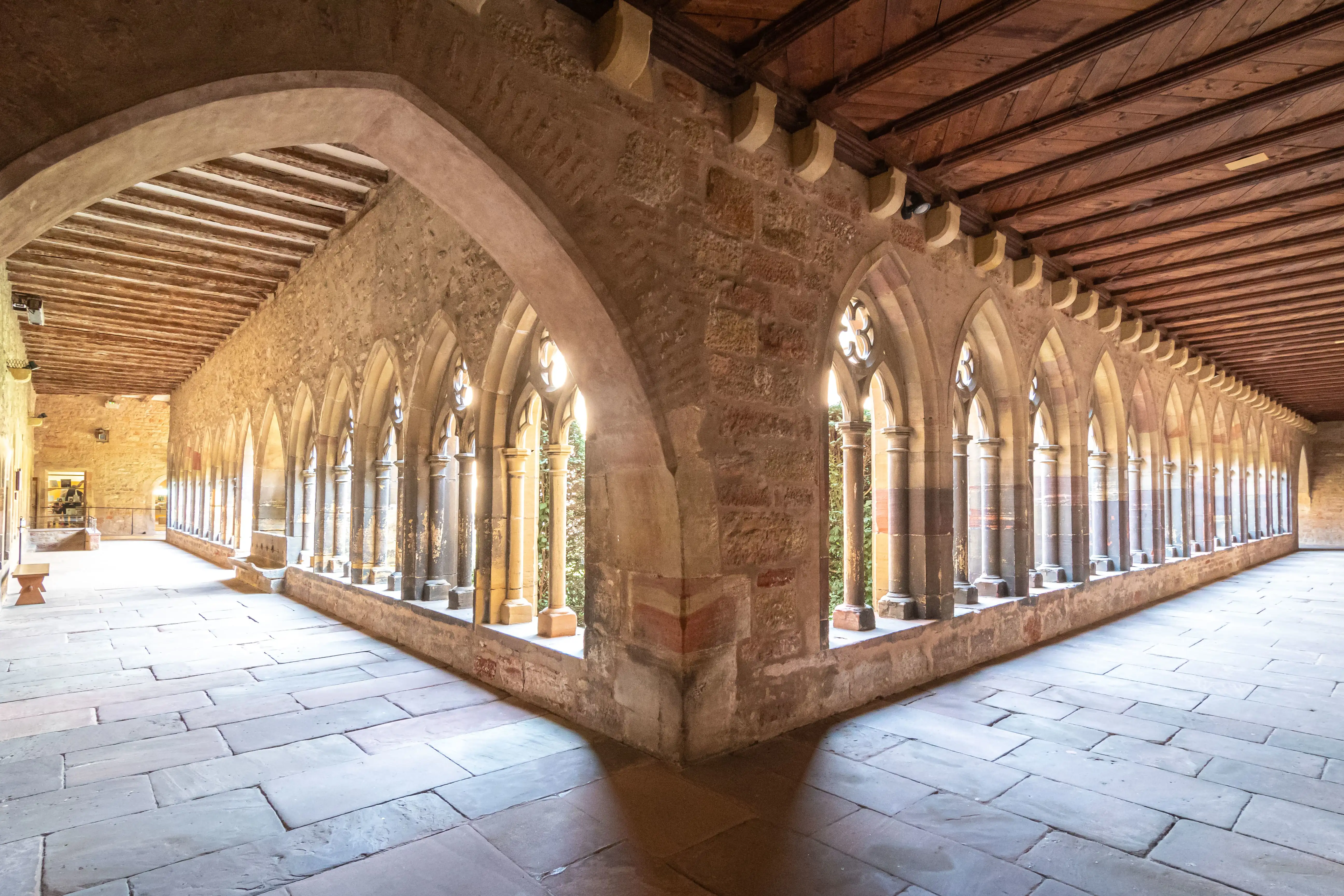 View of the peaceful cloister courtyard at the Unterlinden Museum in Colmar, featuring stone arches, a garden, and historic architecture.
