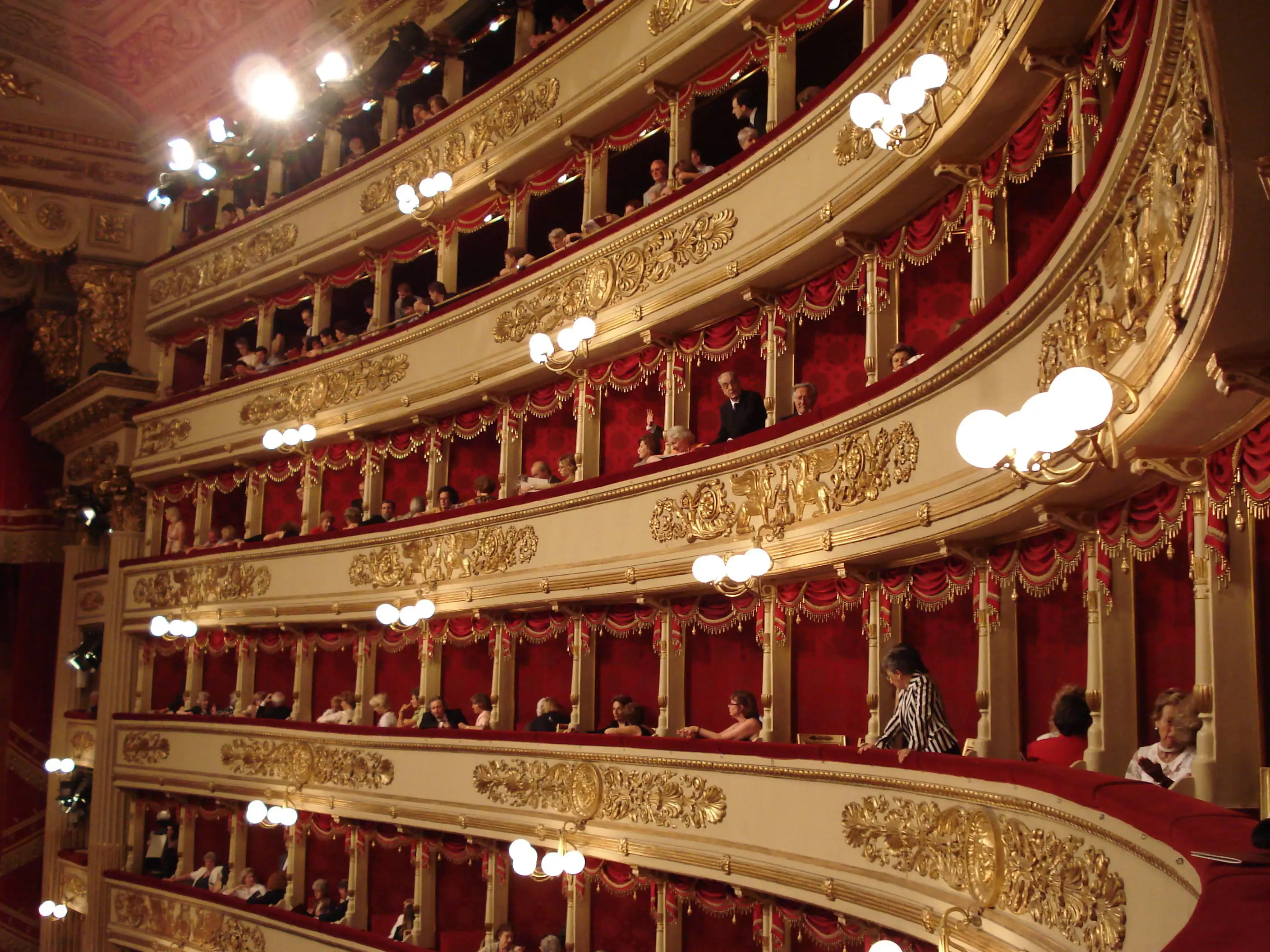 Close-up of red plush seats and gold gilding inside La Scala opera house.