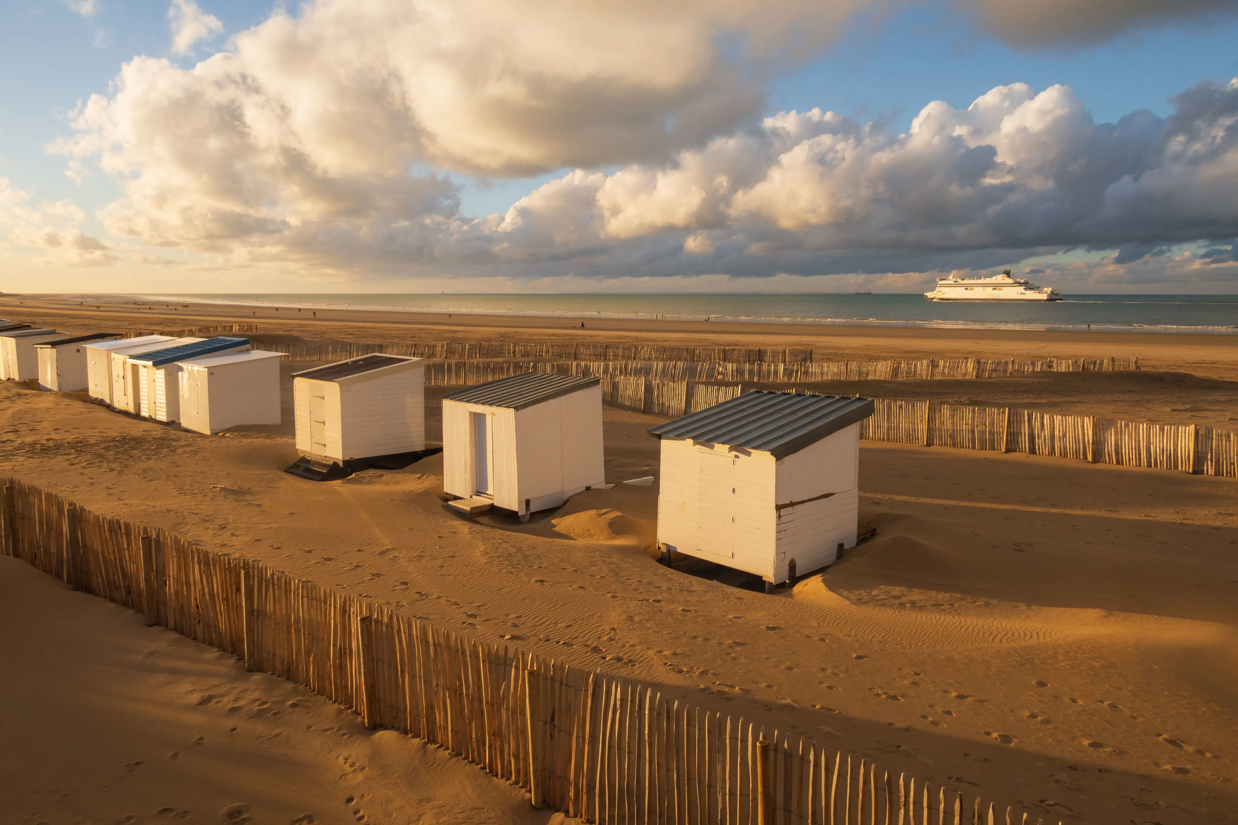 Golden sandy beach at Calais with beach huts along the sand.