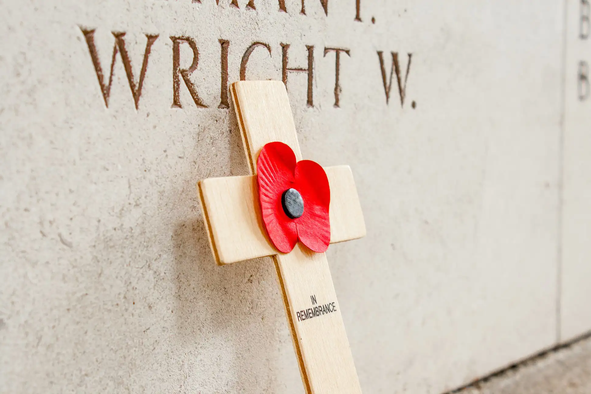 A poppy on a small cross laid at a war memorial