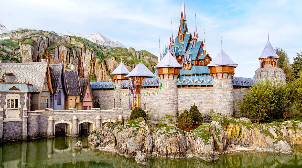 A panoramic view of the rugged mountain terrain and the crystalline structure of the Ice Palace overlooking the Arendelle waterfront.