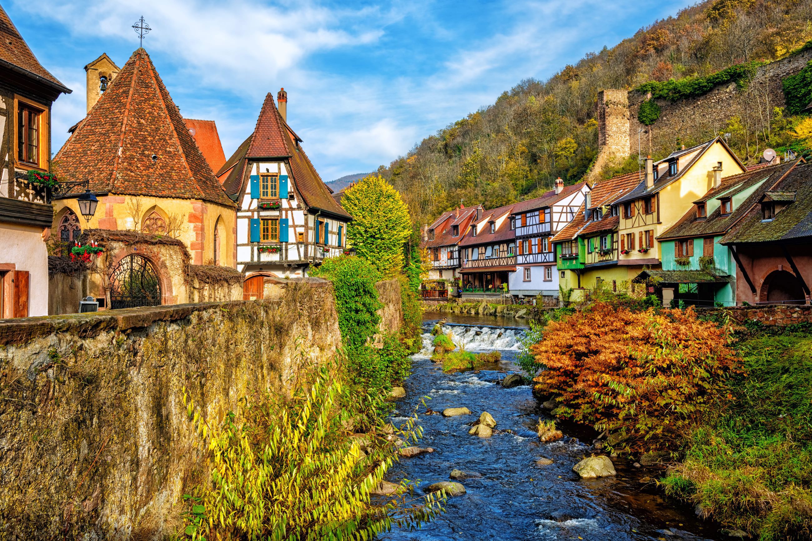 Colourful half-timbered historic houses on either bank of a river in autumn