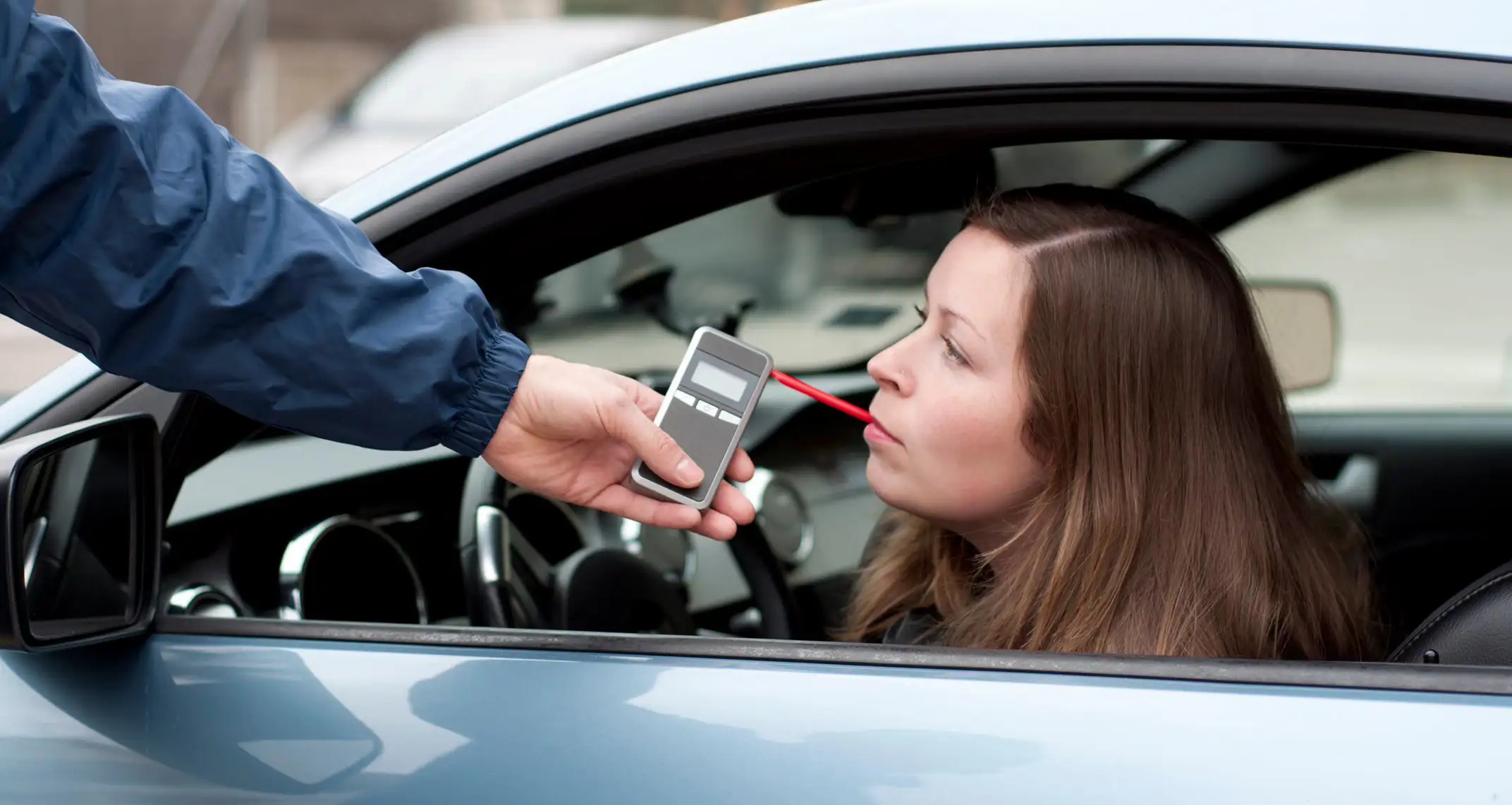 Female driver taking a breathalyser test in a left hand drive car