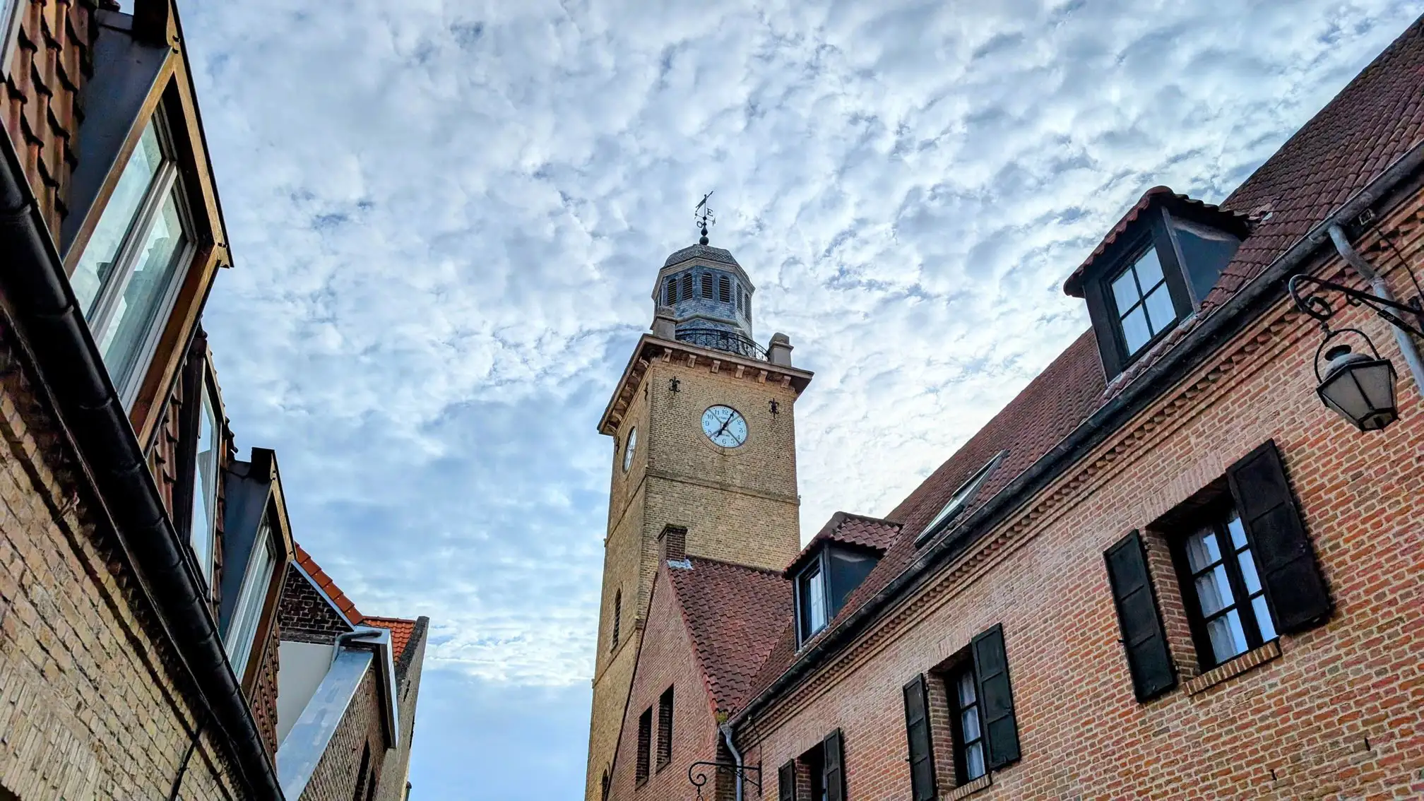 A church belfry overlooking brick buildings in a European town or city