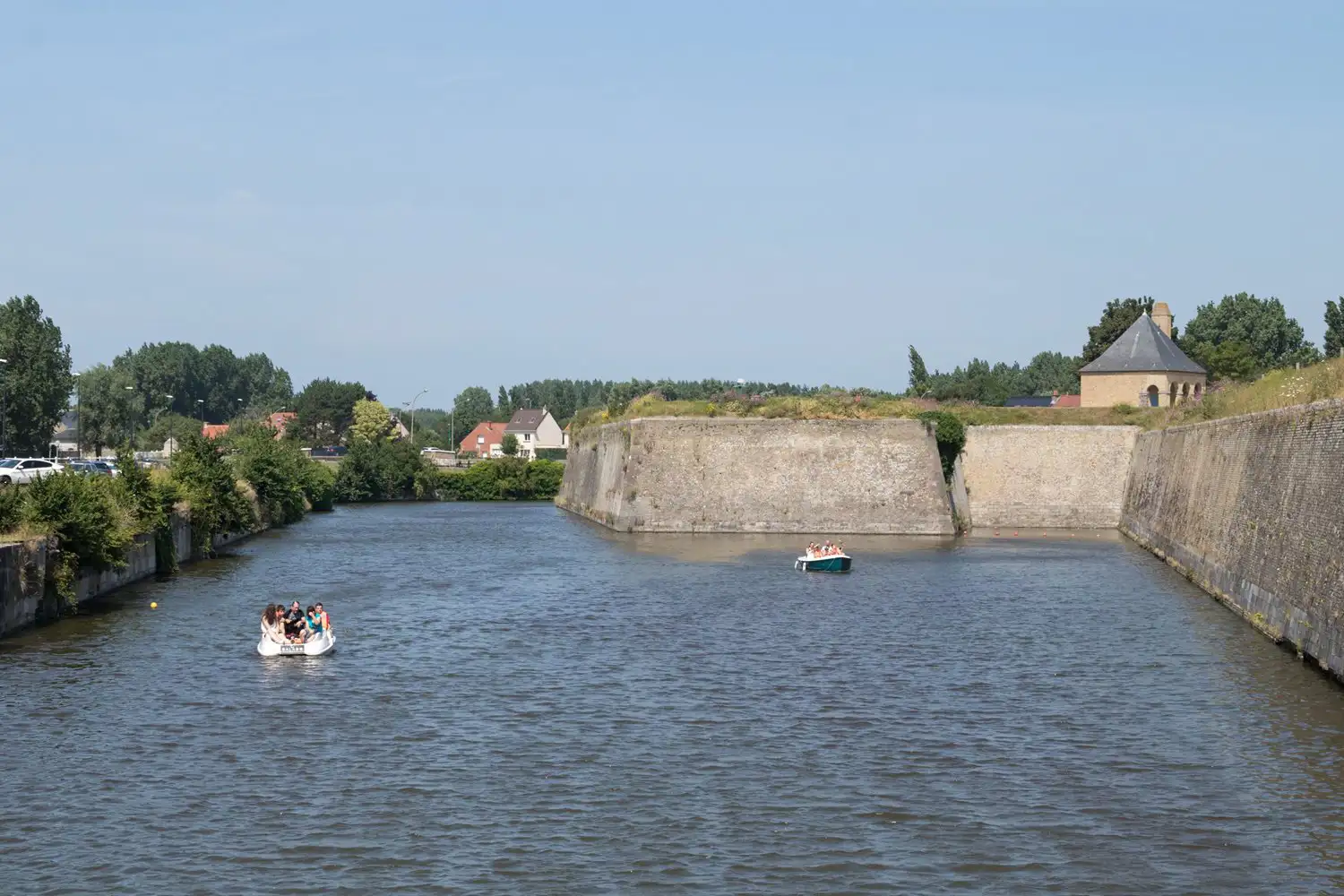 Boats sailing on a river or moat around a walled town