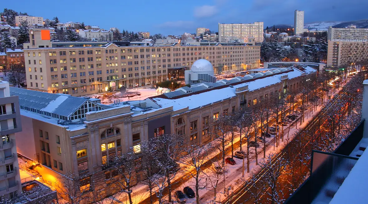 A dome building between two wings of industrial or commercial buildings on a long city street at winter