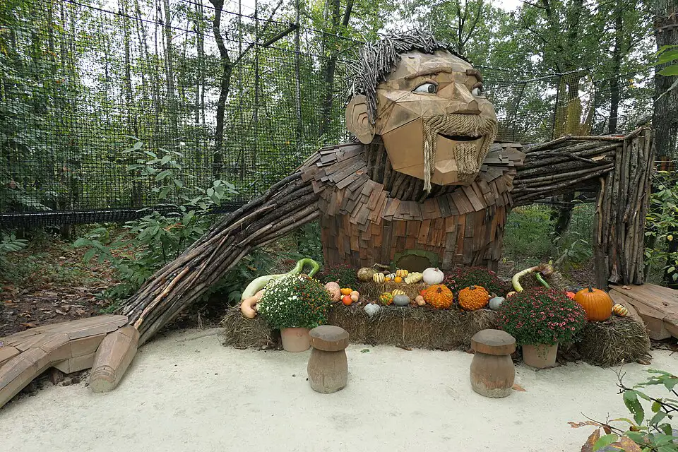 The upper body of wooden giant pulling himself out of the ground. Wooden toadstools and pumpkins are in front of him