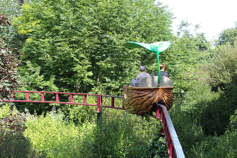 A couple in a walnut themed ride with a red track to pedal along and a leafy canopy overhead.