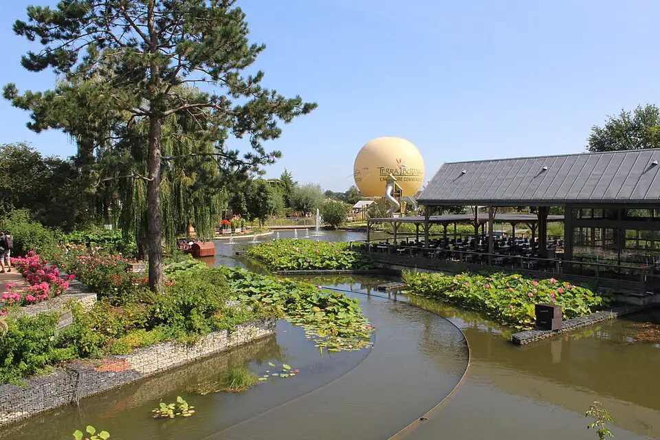 The boat trip attraction at Terra Botanica surrounded by greenery with a blue sky overhead and the hot air balloon in the distance.