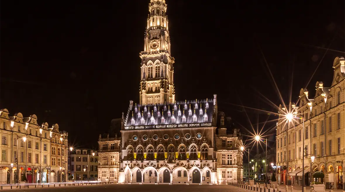 A large cobbled city square illuminated at night