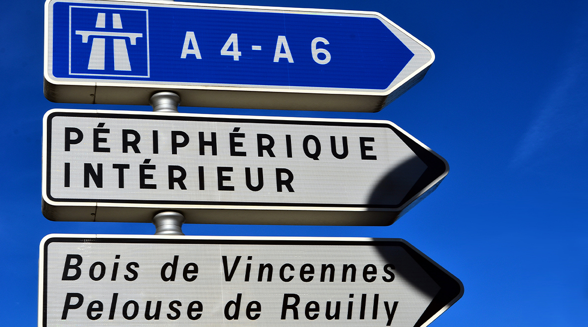Driver point-of-view look at the road signs hanging above a Paris motorway, signalling to Rouen, Orly airport and the Peripherqique Interieure.