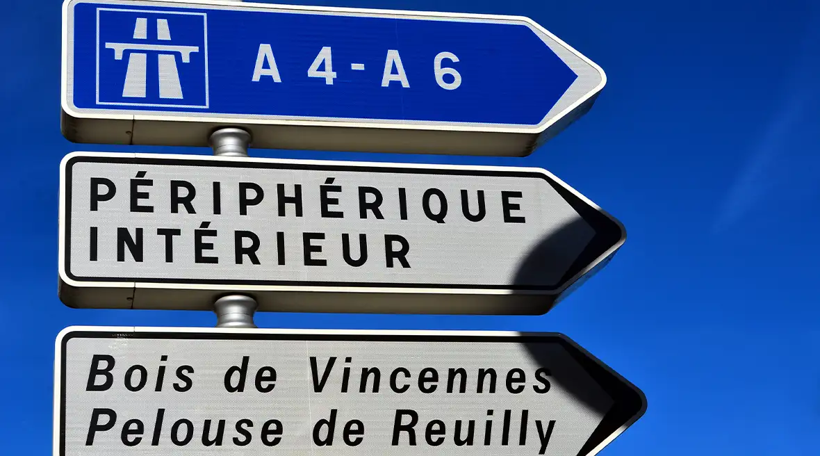 Driver point-of-view look at the road signs hanging above a Paris motorway, signalling to Rouen, Orly airport and the Peripherqique Interieure.