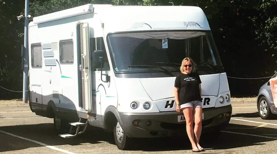 A woman standing at the front of a Hymer motorhome in the Eurotunnel Folkestone departures carp park