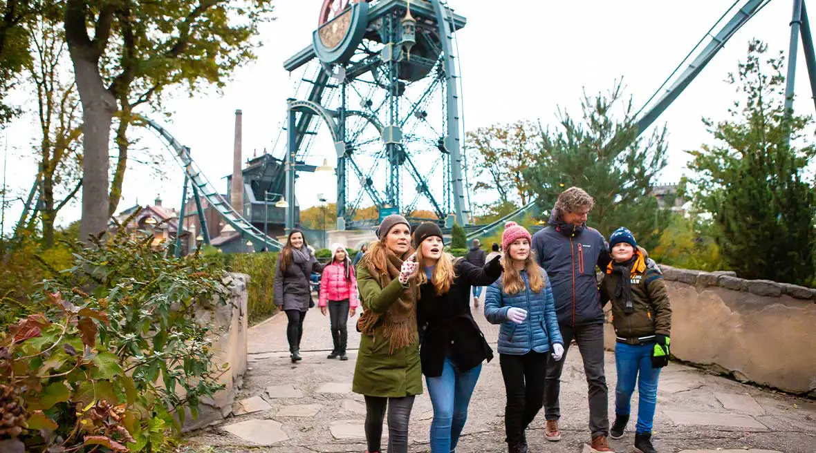 Family group walking through Efteling with rollercoasters in the background