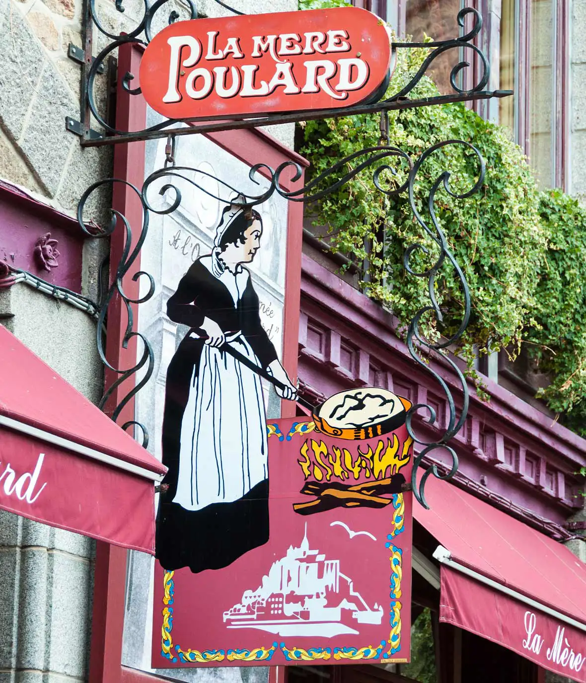 Red sign mounted on a grey wall with white lettering with a cartoon drawing of a woman holding a frying pan in a white apron