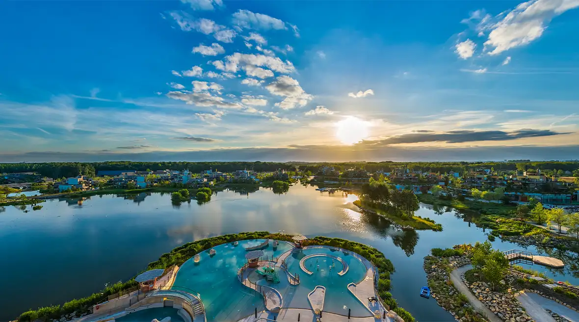 Blue sky and a panoramic aerial view of a large lake surrounded by houses and in the foreground an empty pool complex