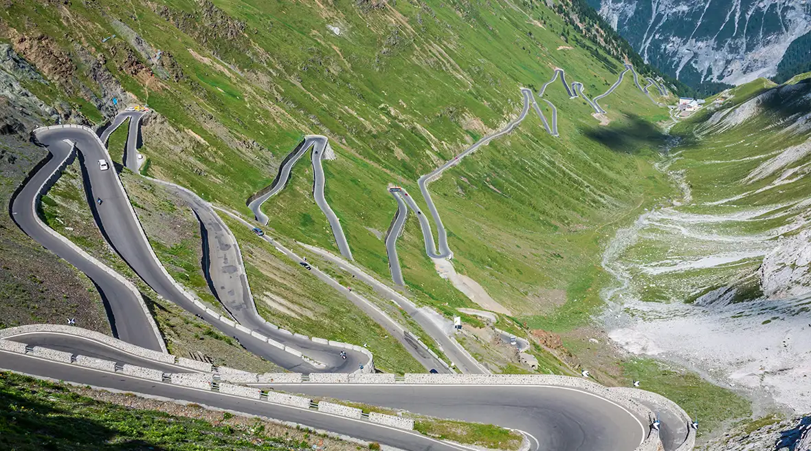 Steep zig zag road travelling down and along the mountain in the Italian Alps