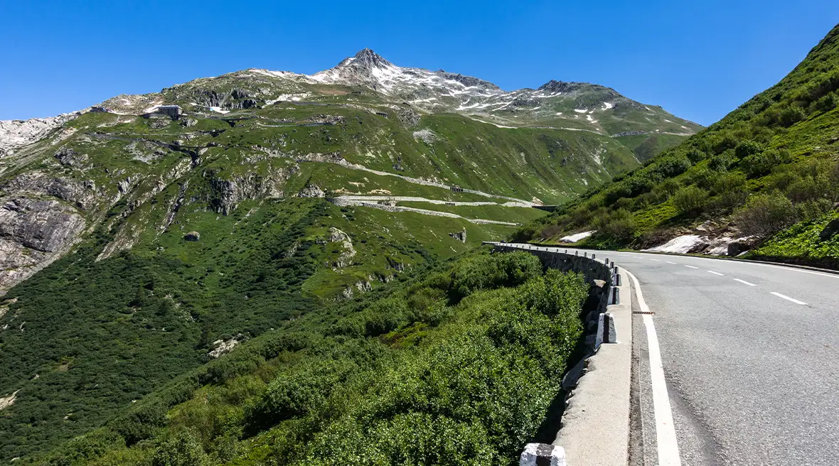 Furka pass road within the Swiss Alps surrounded by stunning greenery
