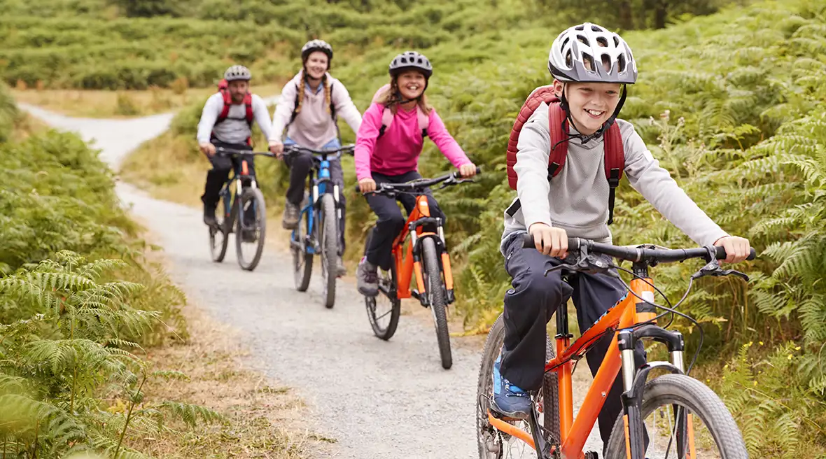 Family of four enjoying riding their bikes through a woodland trail