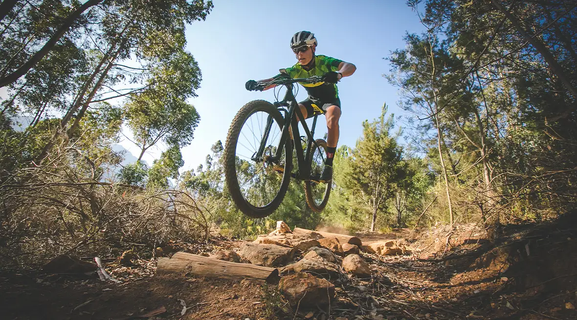 man in cycling outfit speeding downhill on a mountain bike track in the woods