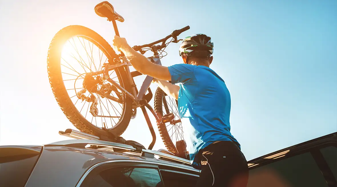 man in blue cycling gear putting on helmet and getting bike from car