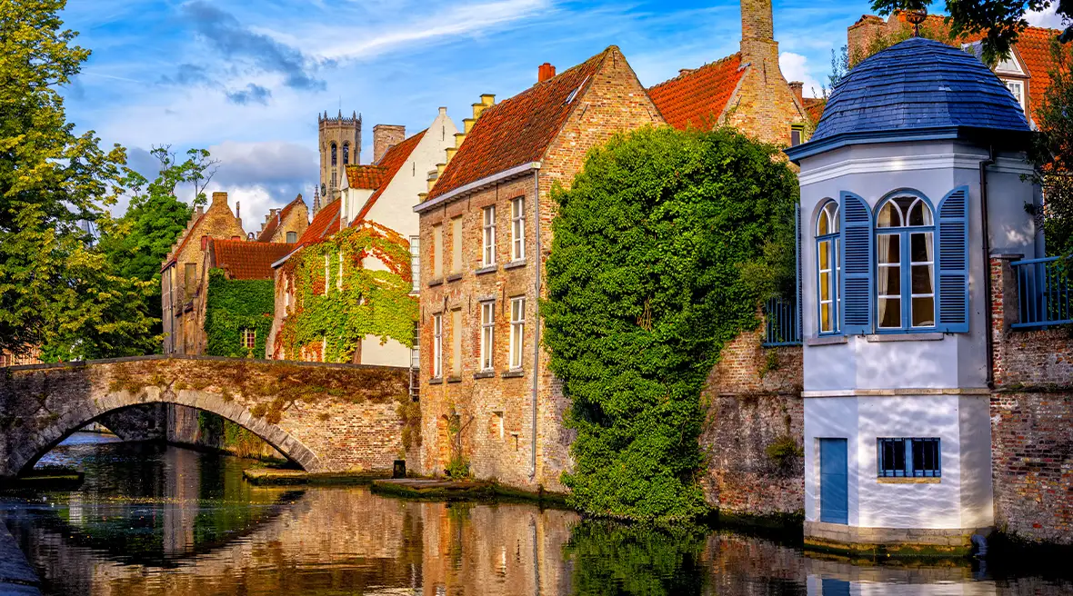 ivy covered medieval buildings on a river with a bridge