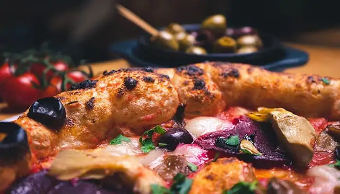 Kleurrijke pizza voor een tros tomaten en olijven