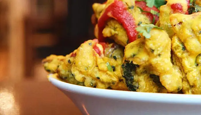 Gele curry met tomaten en peterselie in een witte kom tegen wazige achtergrond