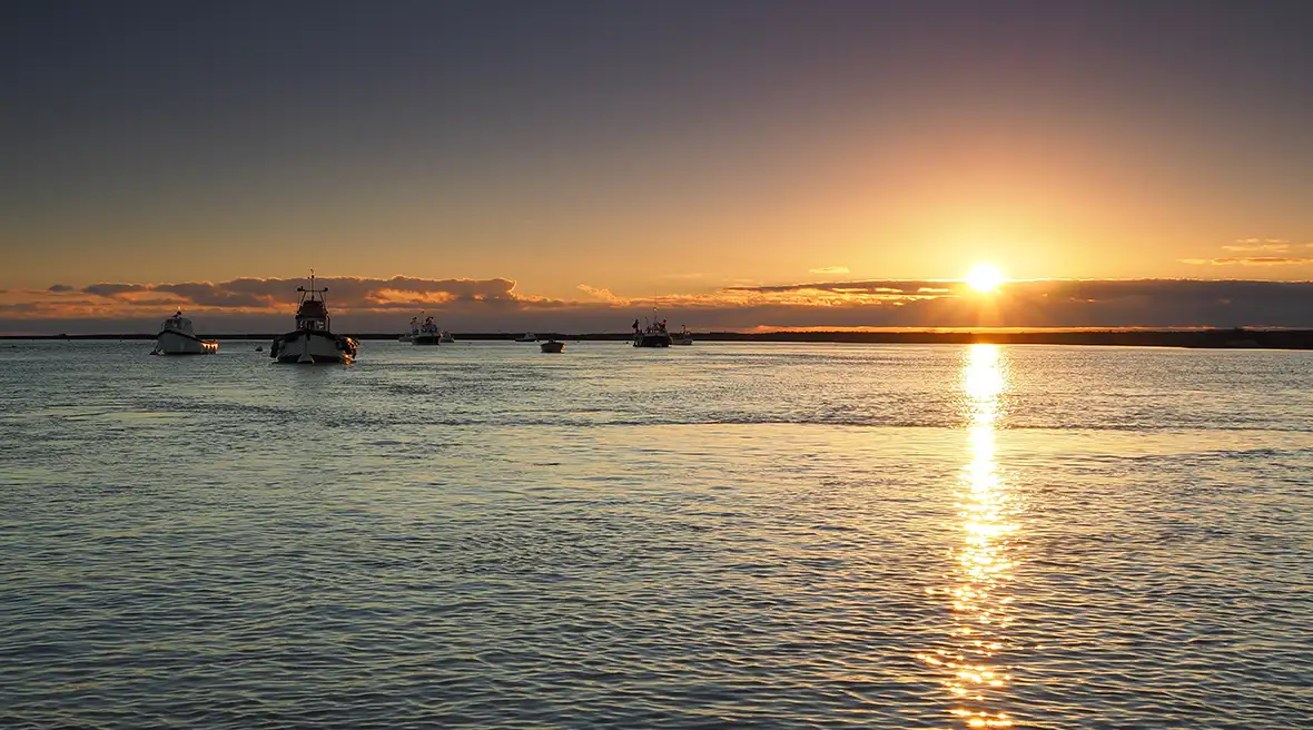 Vissersboten op kalme zee bij zonsondergang