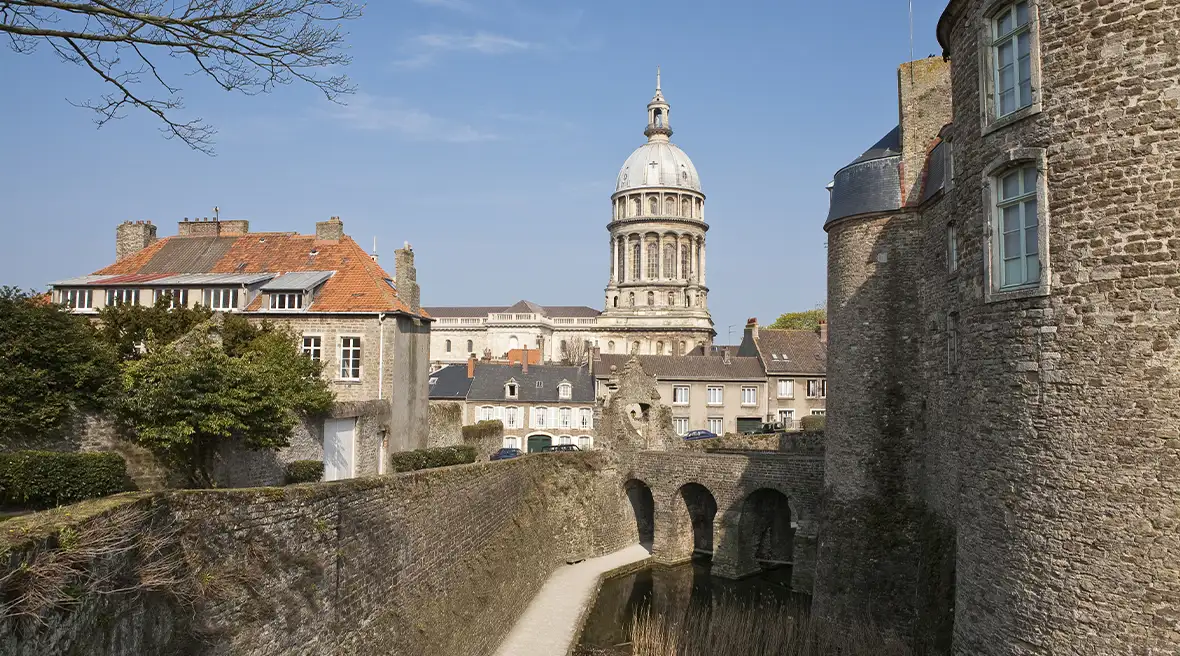 A view of the Basilica of Notre-Dame from the Chateau De Boulogne-sur-Mer under a blue sky.