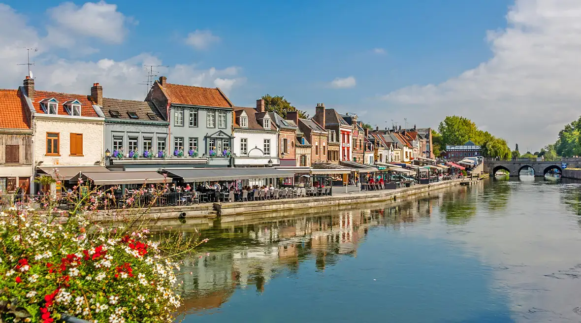 riverside pretty buildings with bridge in the distance and flowers in the foreground