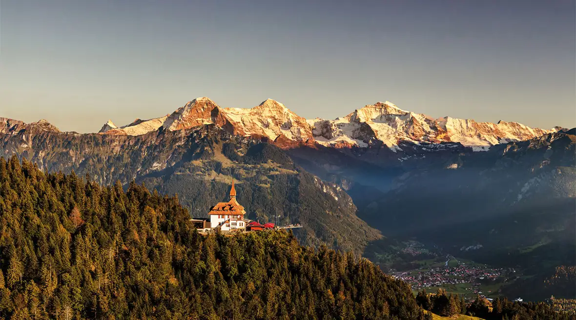 An aerial view of Harder Kulm peak and panorama restaurant with the mountains beyond Interlaken behind