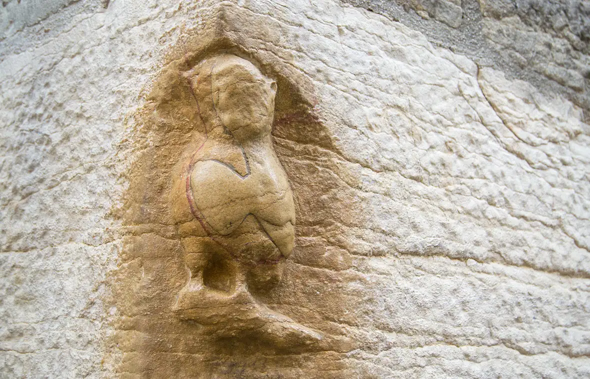 A stone owl carved into a white stone wall