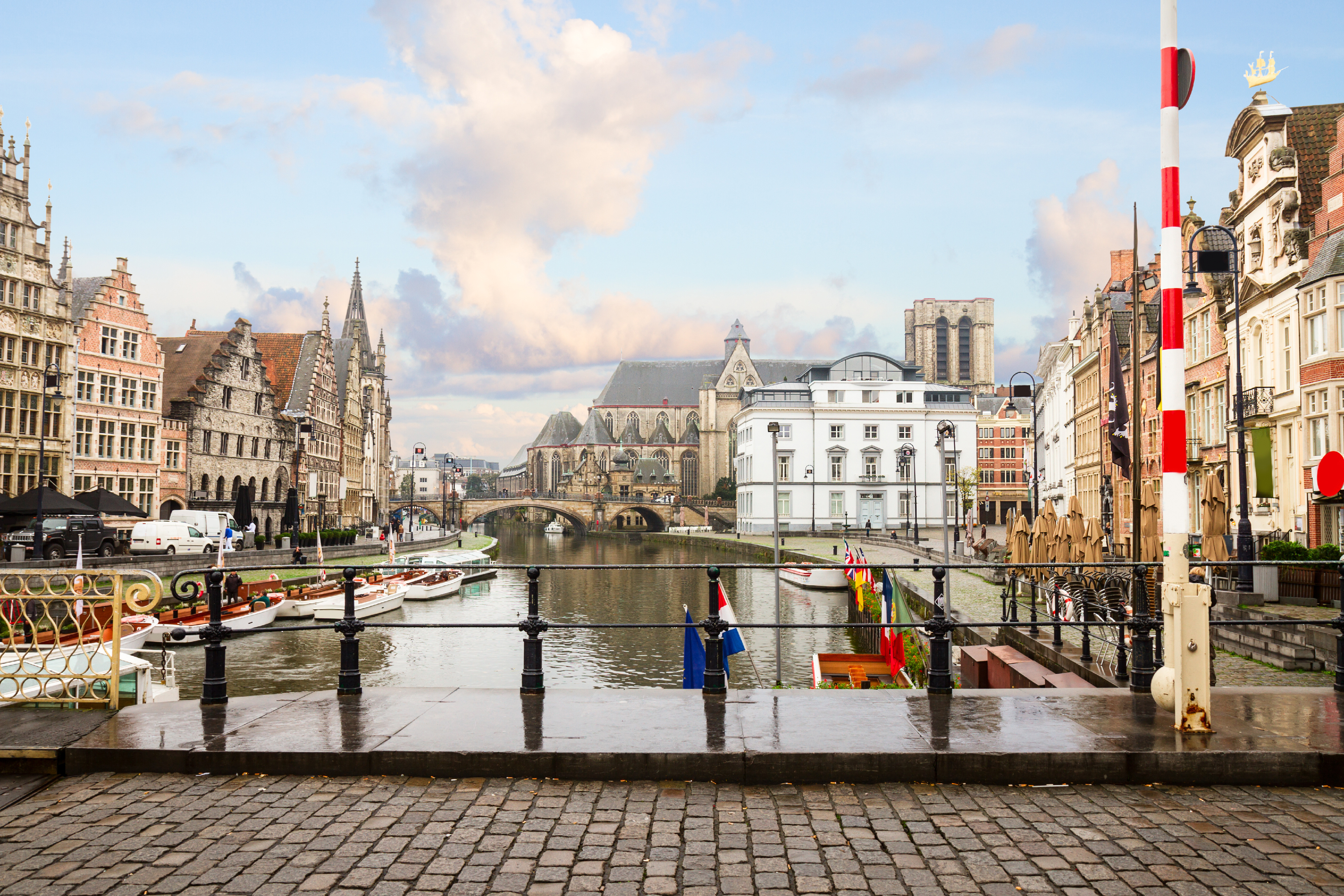 A view of Graslei quay in Ghent, looking over the river which is surrounded by historic buildings on a bright sunny day.