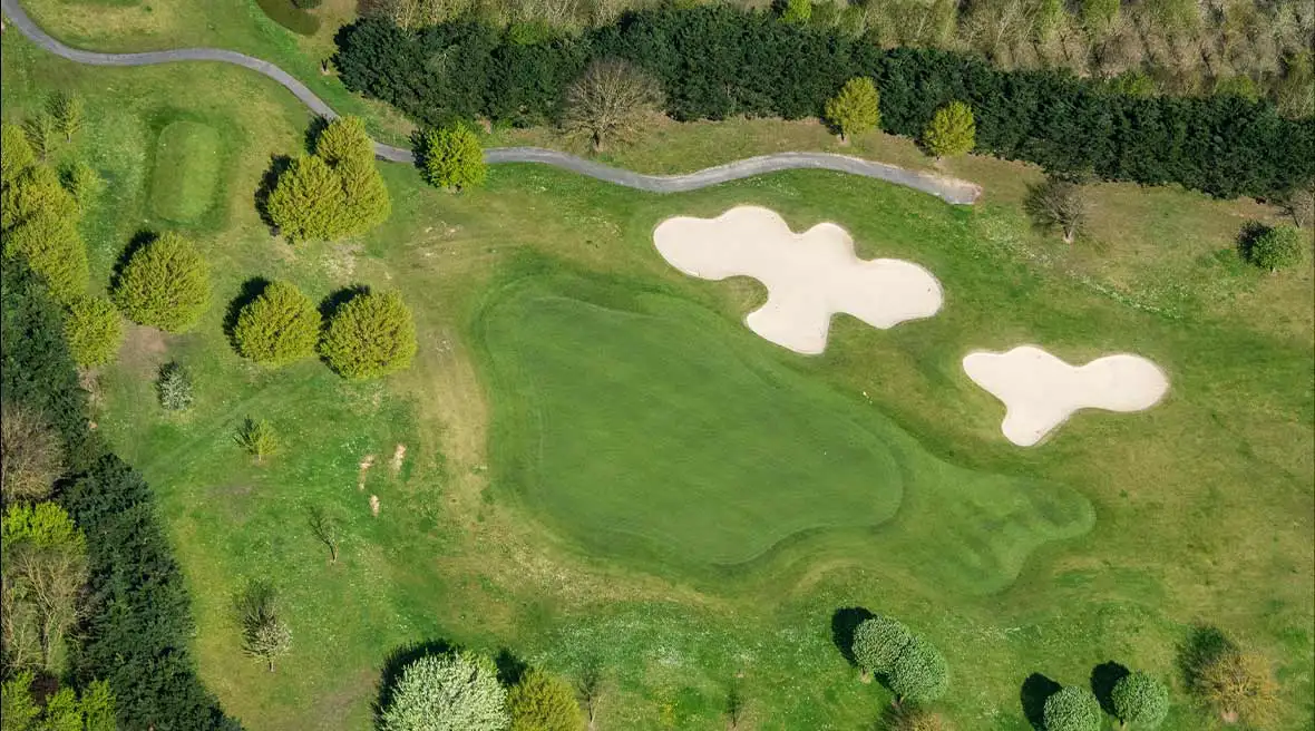 Panoramic view of a golf course with stretches of green and shaped sand banks