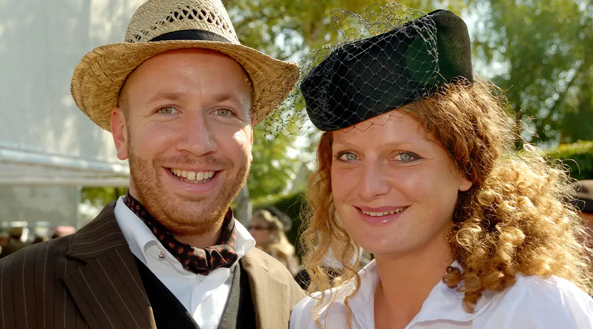 Portrait d’un couple habillé dans le style des années 50. L’homme porte un panama et la dame un bibi noir